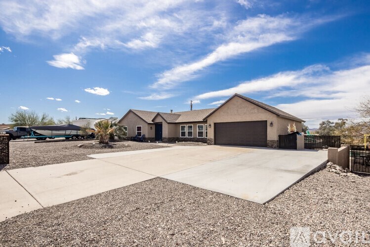 A large house with a garage is surrounded by a gravel driveway.