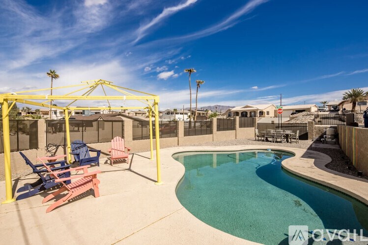 A pool with a yellow canopy and lounge chairs.