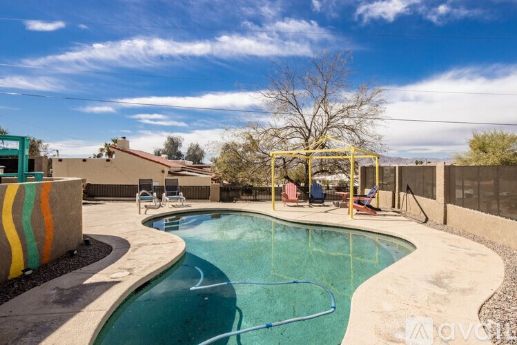A small pool with a slide and a tree in the background.