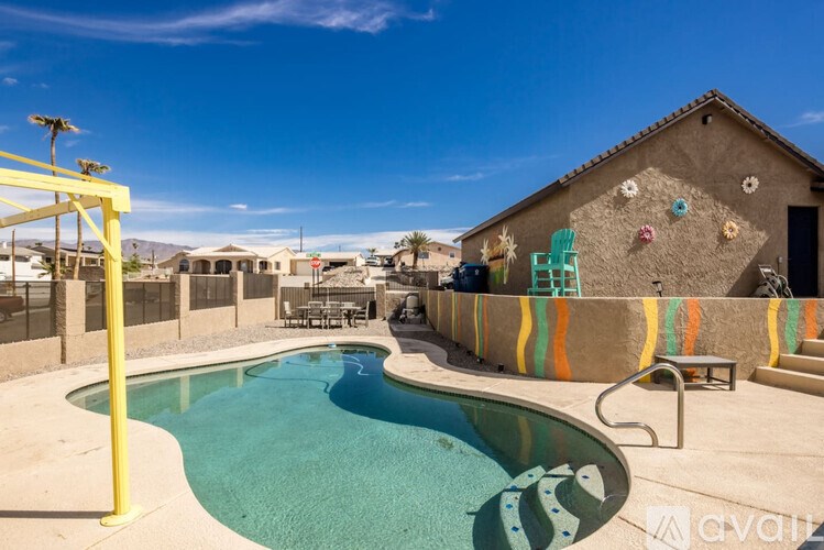 A pool with a slide and a house with a mural on the side.
