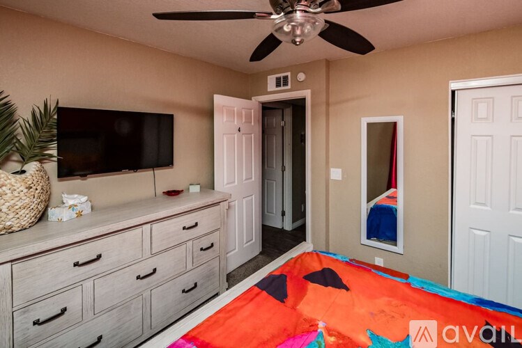 A room with a ceiling fan and a television on a cabinet.