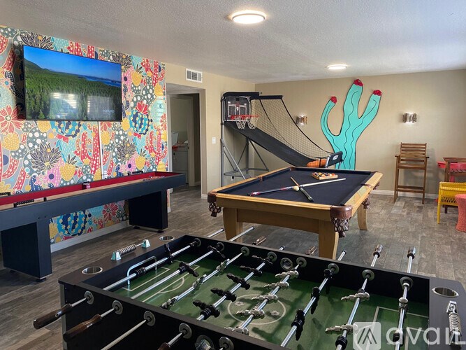 A foosball table is in the middle of a room with a pool table and a TV.