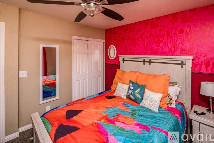 A bedroom with a white bed and a ceiling fan.