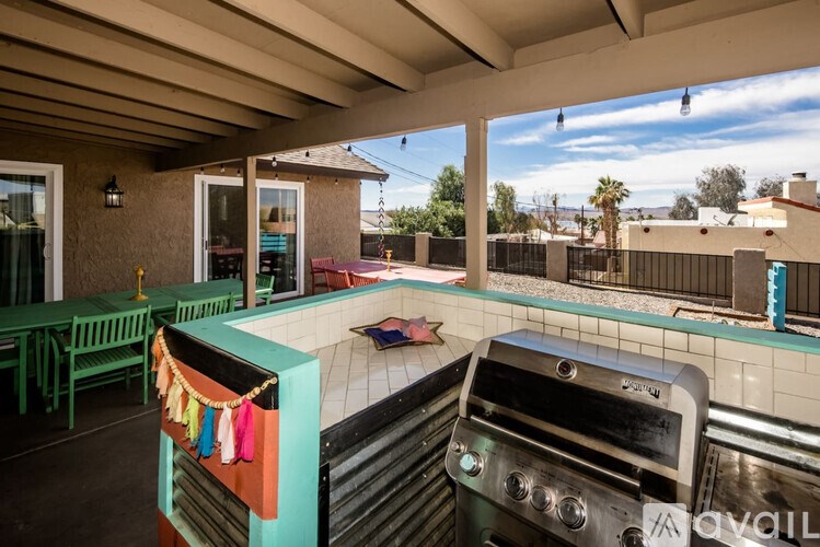 A patio with a grill and a table with chairs.