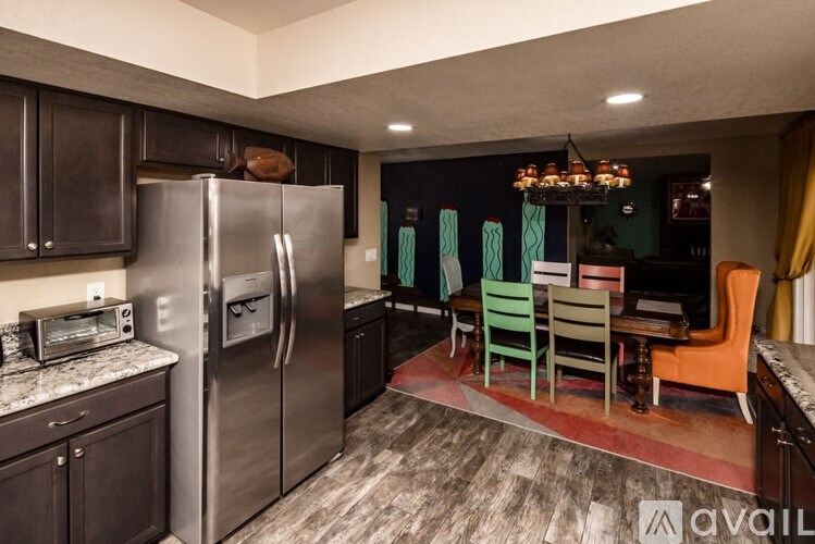 A kitchen with a refrigerator, microwave, and a dining table with chairs.