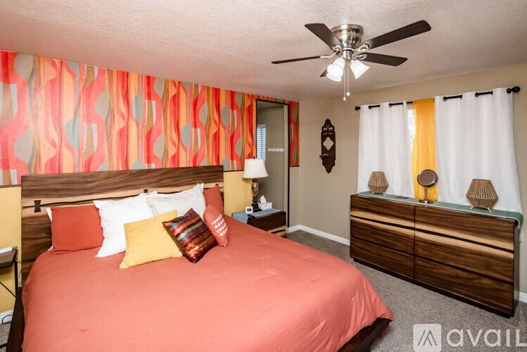 A bedroom with a bed, dresser, and ceiling fan.