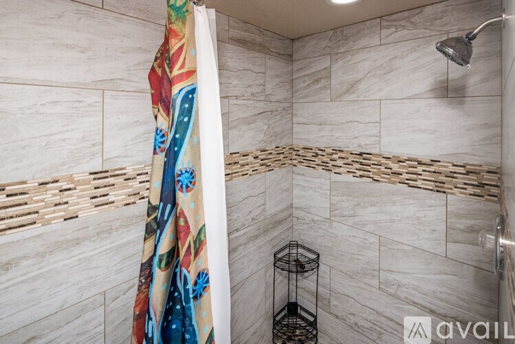 A shower area with a shower head and a glass of water.