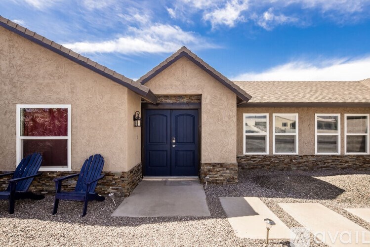 A house with a blue door and two blue chairs in front.