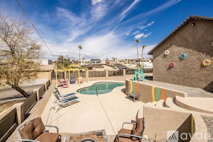 A pool surrounded by chairs and a house with a balcony.
