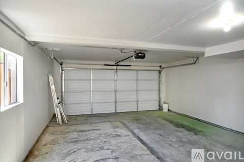 A spacious garage with a white door and a ladder.