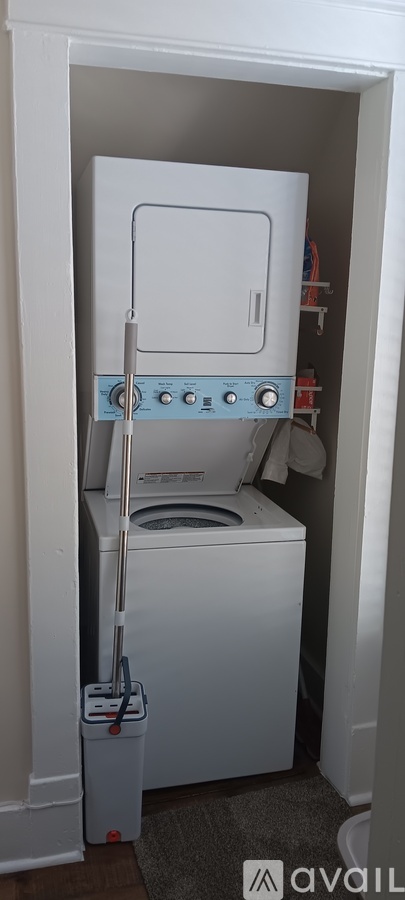 A white dryer is in a small white closet.