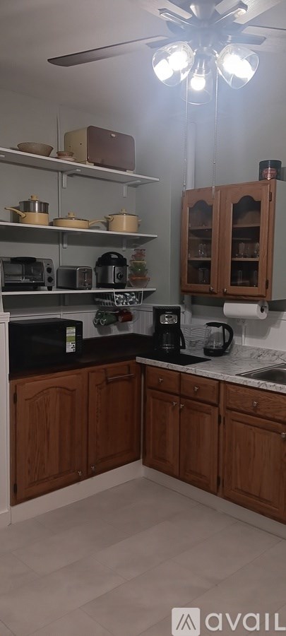 A kitchen with wooden cabinets and a ceiling fan.
