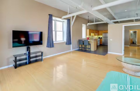 A spacious living room with a television and a glass coffee table.