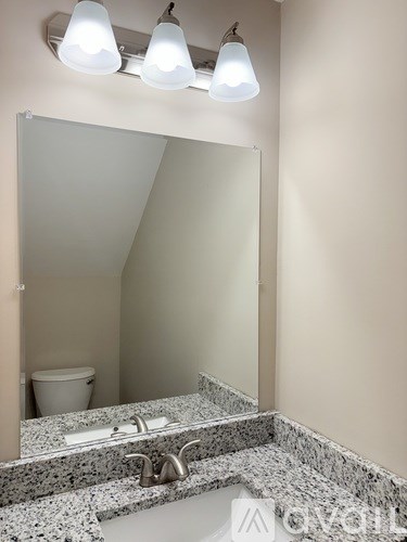 A bathroom with a granite counter top and a large mirror.