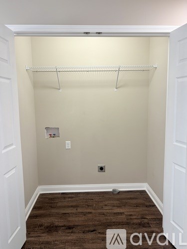 A white closet with a wooden floor and a white shelf.