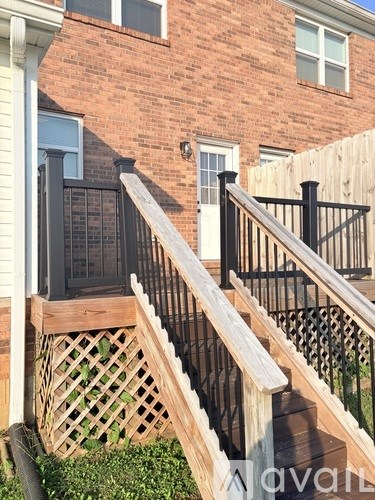 A wooden staircase with a black railing leads up to a brick building.