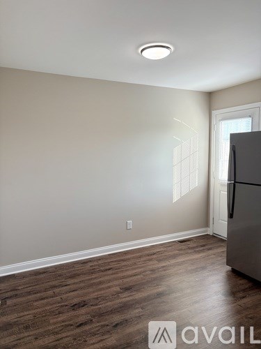 A kitchen with a refrigerator and wooden flooring.