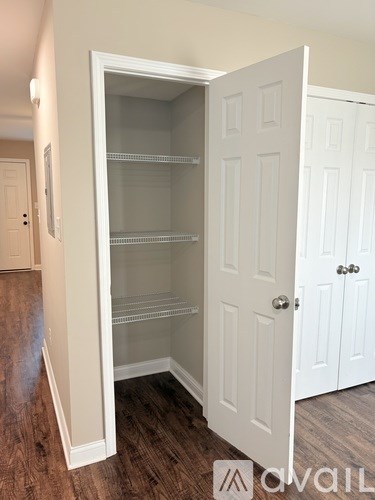 A white door with a glass panel is open in a room with wood flooring.