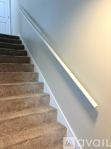 A staircase with a carpeted runner and a white wall.