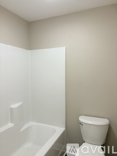 A white toilet sits next to a white bathtub in a bathroom.