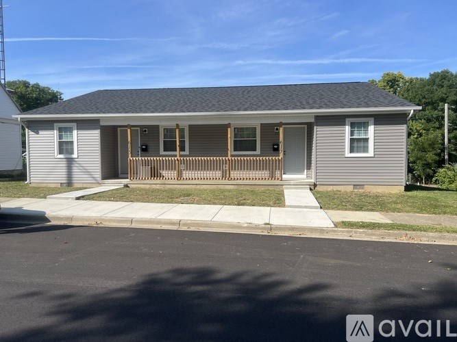A house with a grey siding and a brown wooden porch.