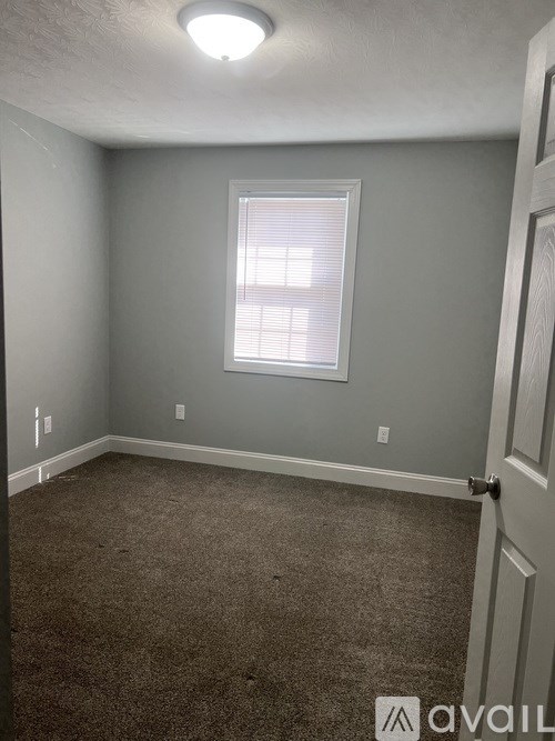 A room with a carpeted floor and a window with blinds.