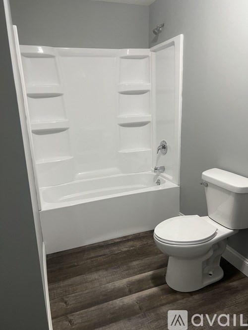 A white toilet sits next to a walk-in shower in a bathroom.