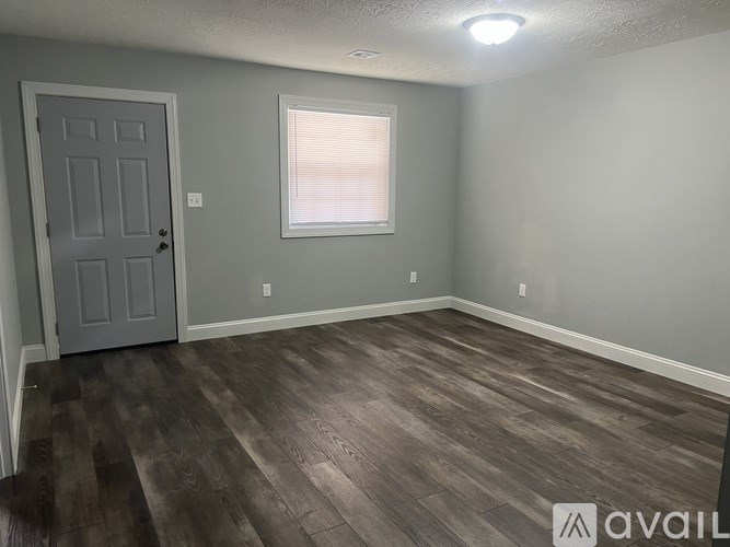 A room with a grey door and a window with blinds.