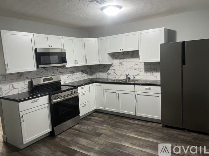 A kitchen with white cabinets and a black refrigerator.