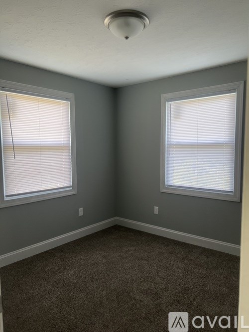 A room with two windows and carpeted floor.