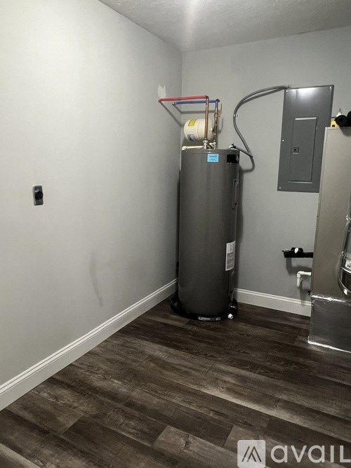 A room with a water heater and a toilet.