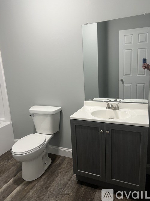 A bathroom with a toilet, sink and cabinet.