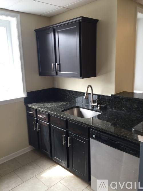 A kitchen with black cabinets and granite countertops.