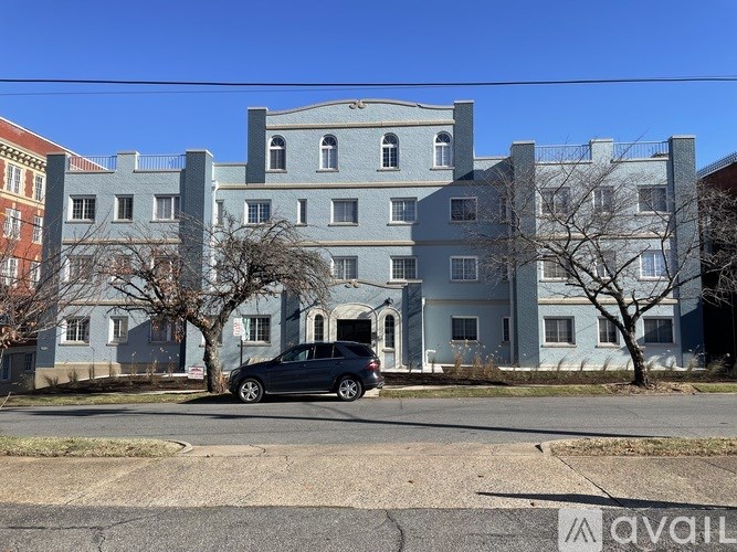A large grey building with a black car parked in front.
