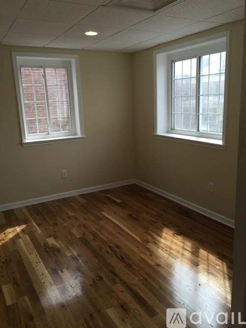 A room with wooden floors and two windows.