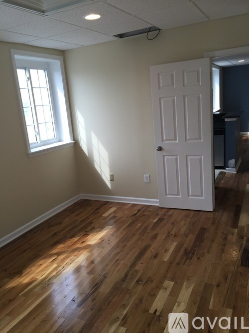 A room with a white door and a window with sunlight coming through.