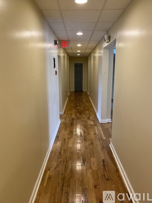 A long hallway with wood floors and white walls.