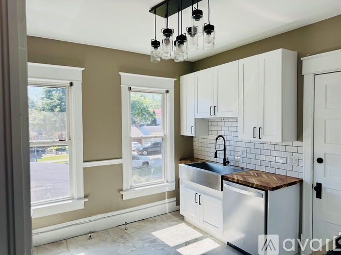 A kitchen with white cabinets and a black faucet.
