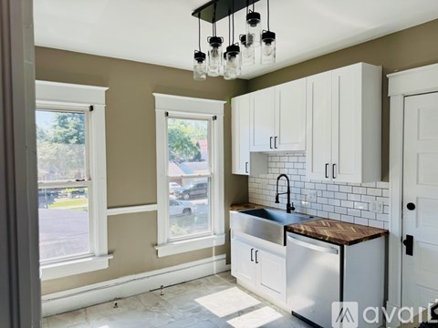 A kitchen with white cabinets and a black faucet.