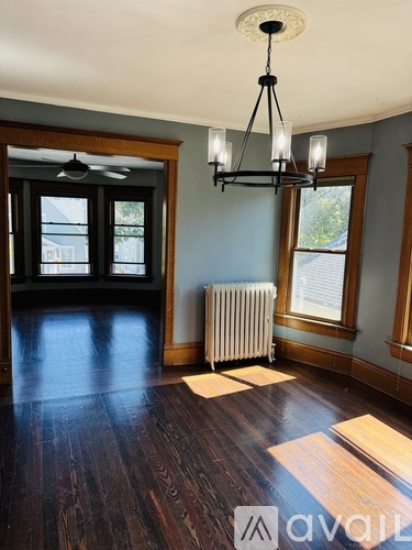 A room with wooden floors and a chandelier hanging from the ceiling.