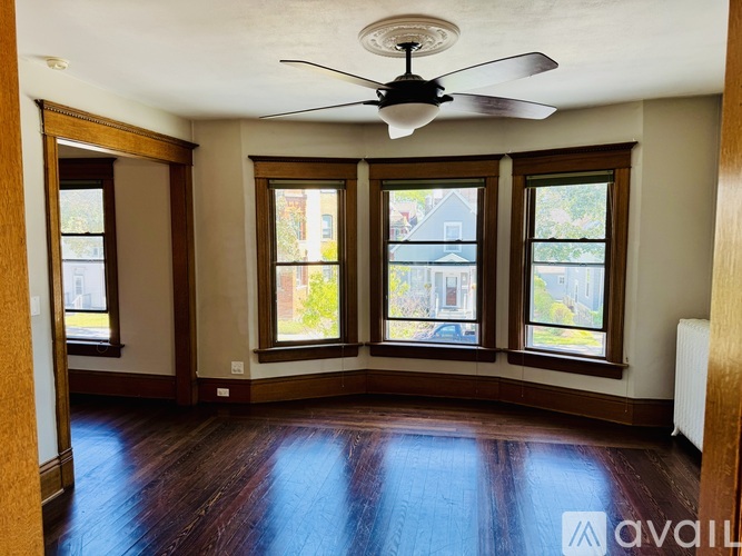 A room with a ceiling fan and three windows.