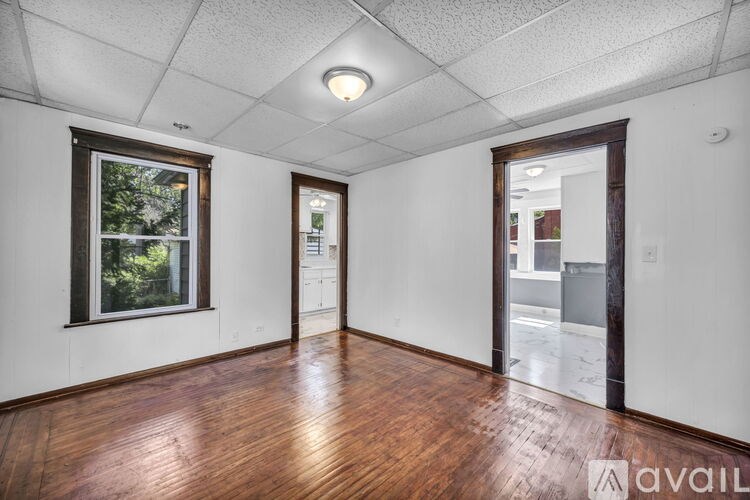 A room with wooden floors and a window showing greenery outside.