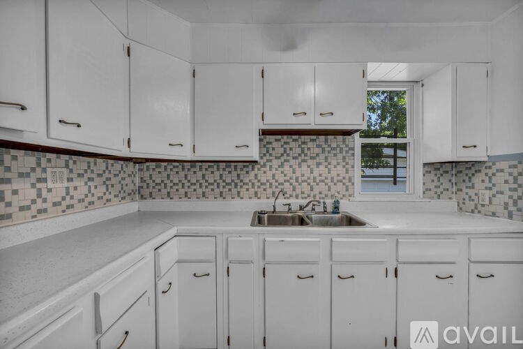 A kitchen with white cabinets and a checkered backsplash.
