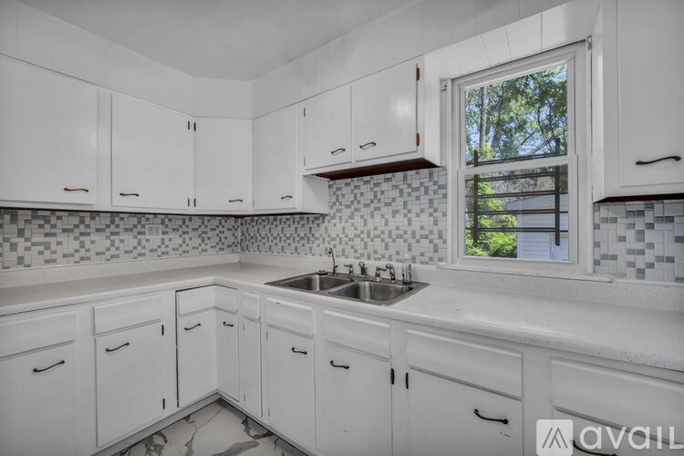 A kitchen with white cabinets and a checkered backsplash.
