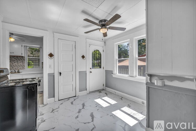 A kitchen with a black fridge and a ceiling fan.