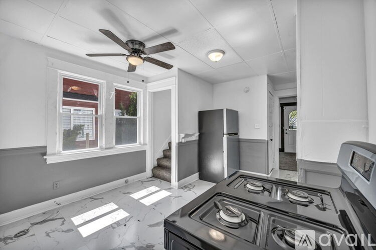 A kitchen with a stove top oven and a fan on the ceiling.