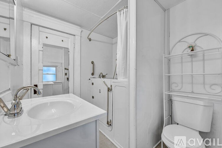 A white bathroom with a sink, mirror, and toilet.
