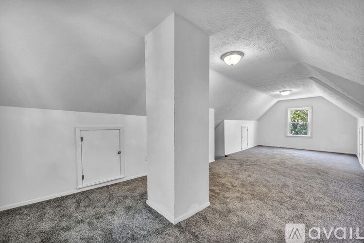 A spacious room with a carpeted floor and a window.