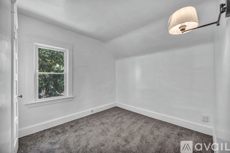 A room with a window and a carpeted floor.