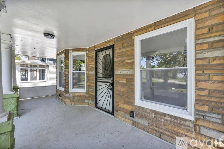 A patio area with a black gate and a brick wall.